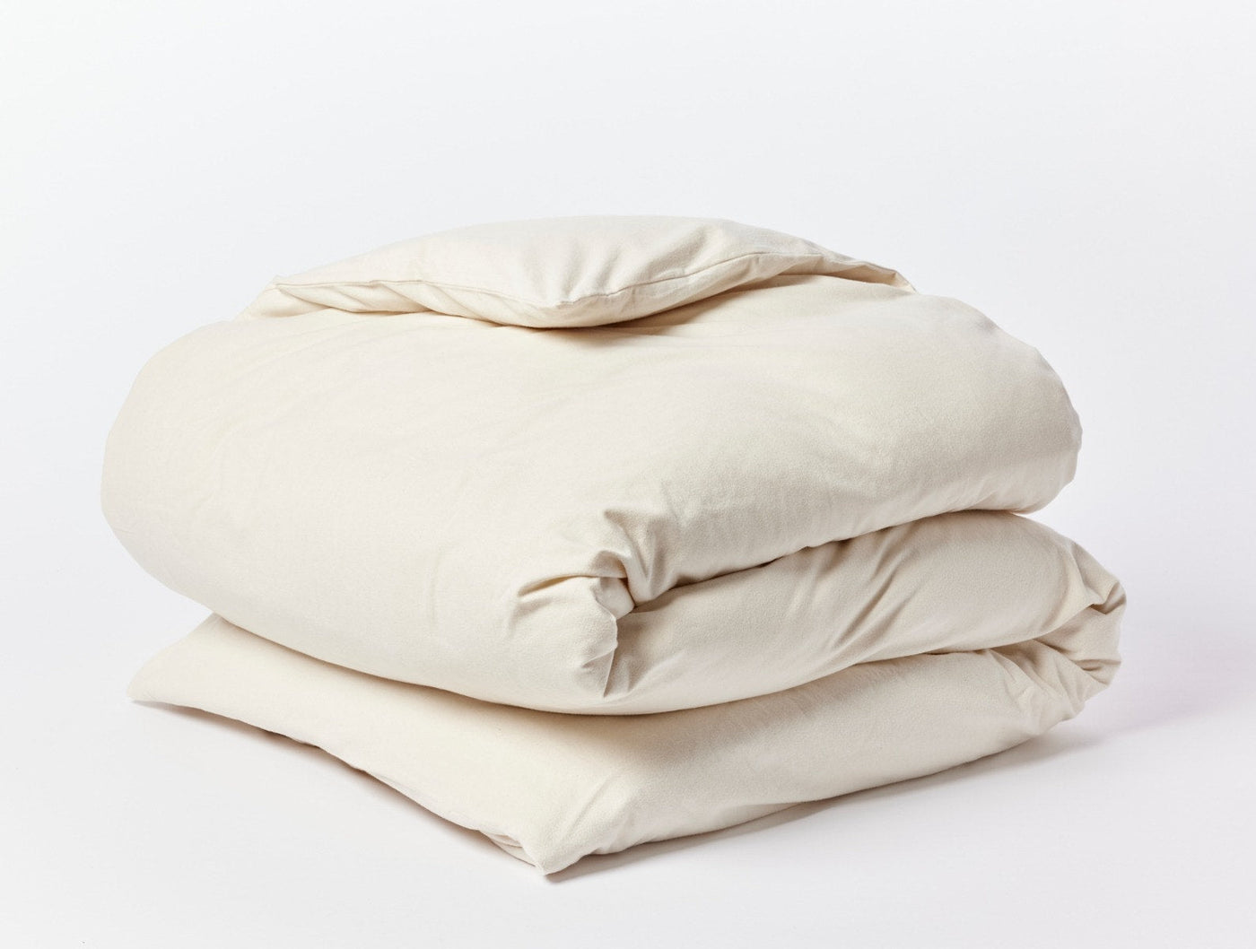 Close-up of folded ivory Coyuchi Cloud Brushed Flannel duvet cover showing soft texture.