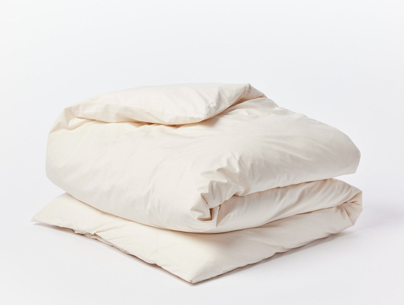 Ivory percale duvet cover folded and stacked, showing natural off-white tone and soft drape.
