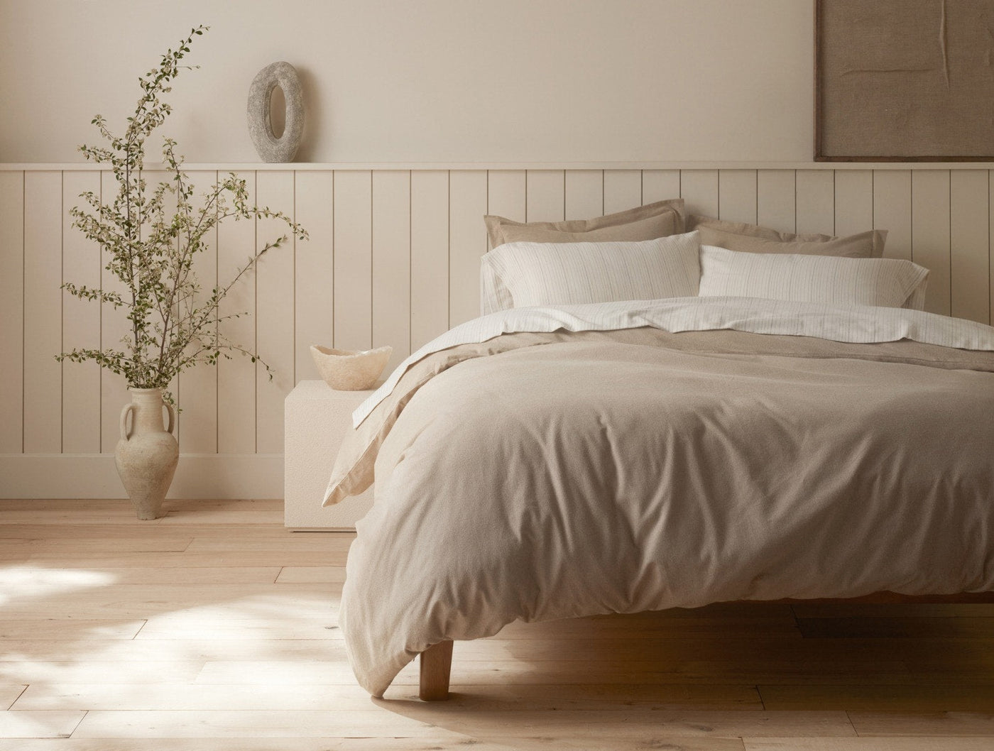 Warm sand flannel duvet on a low wood bed, styled with ivory pillows in a serene neutral room.