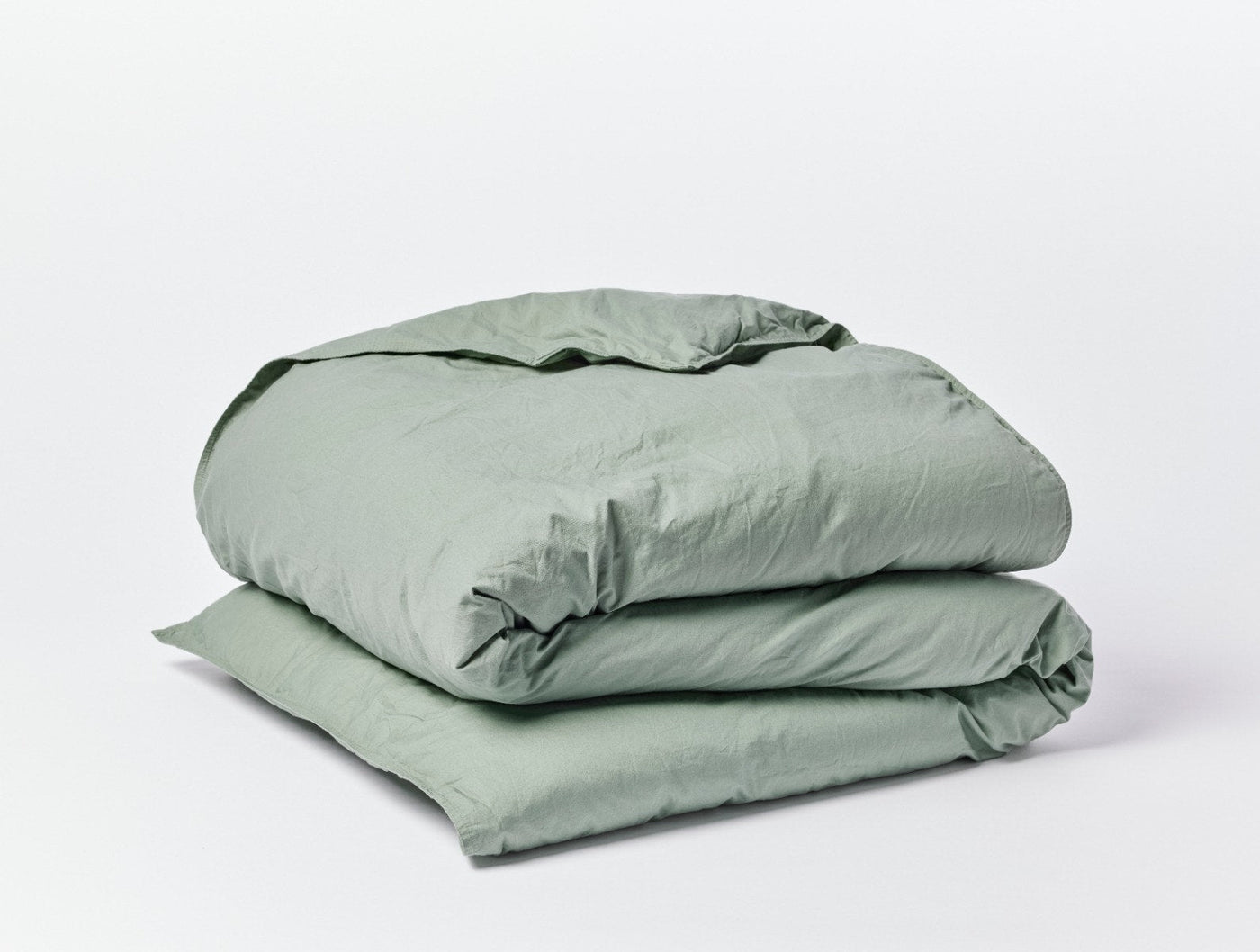 Sage green Coyuchi Crinkled Percale duvet cover folded, showing natural crinkled texture.
