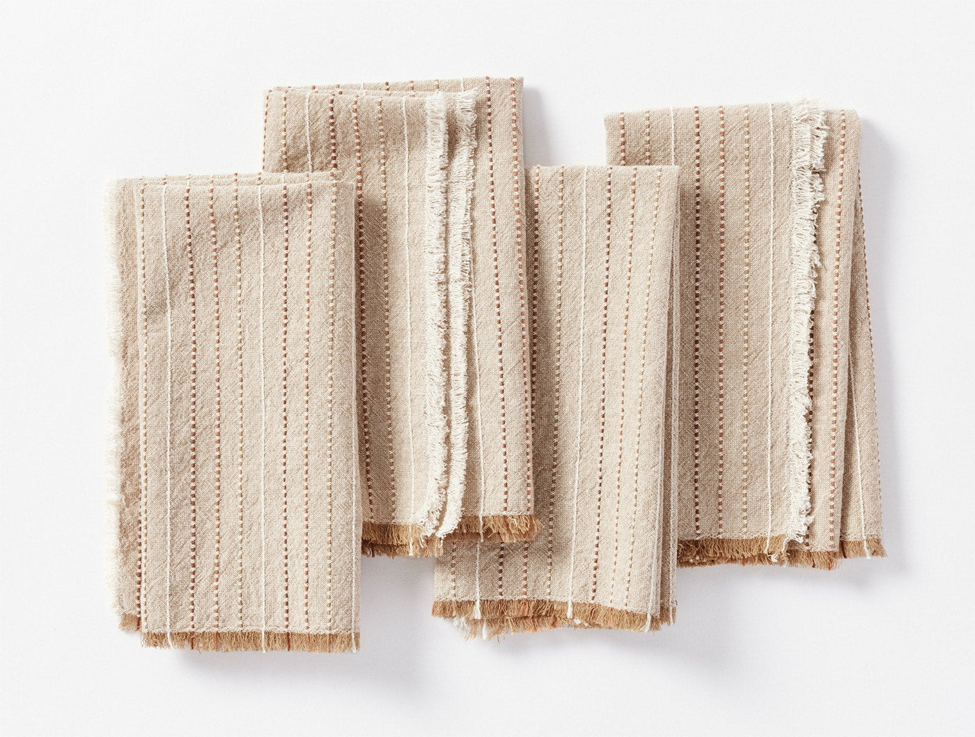 Set of four Coyuchi Fringe Stripe napkins in natural, folded flat, showing striped texture and fringe edges.