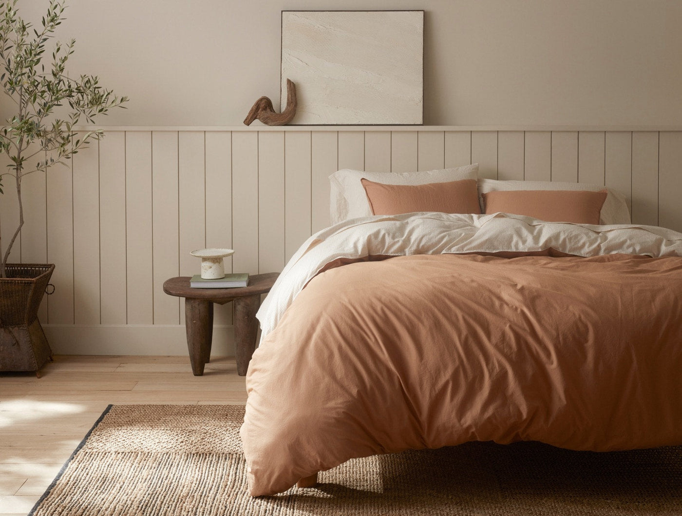 Coyuchi Crinkled Percale duvet cover in terracotta, styled on a bed in a warm neutral bedroom.