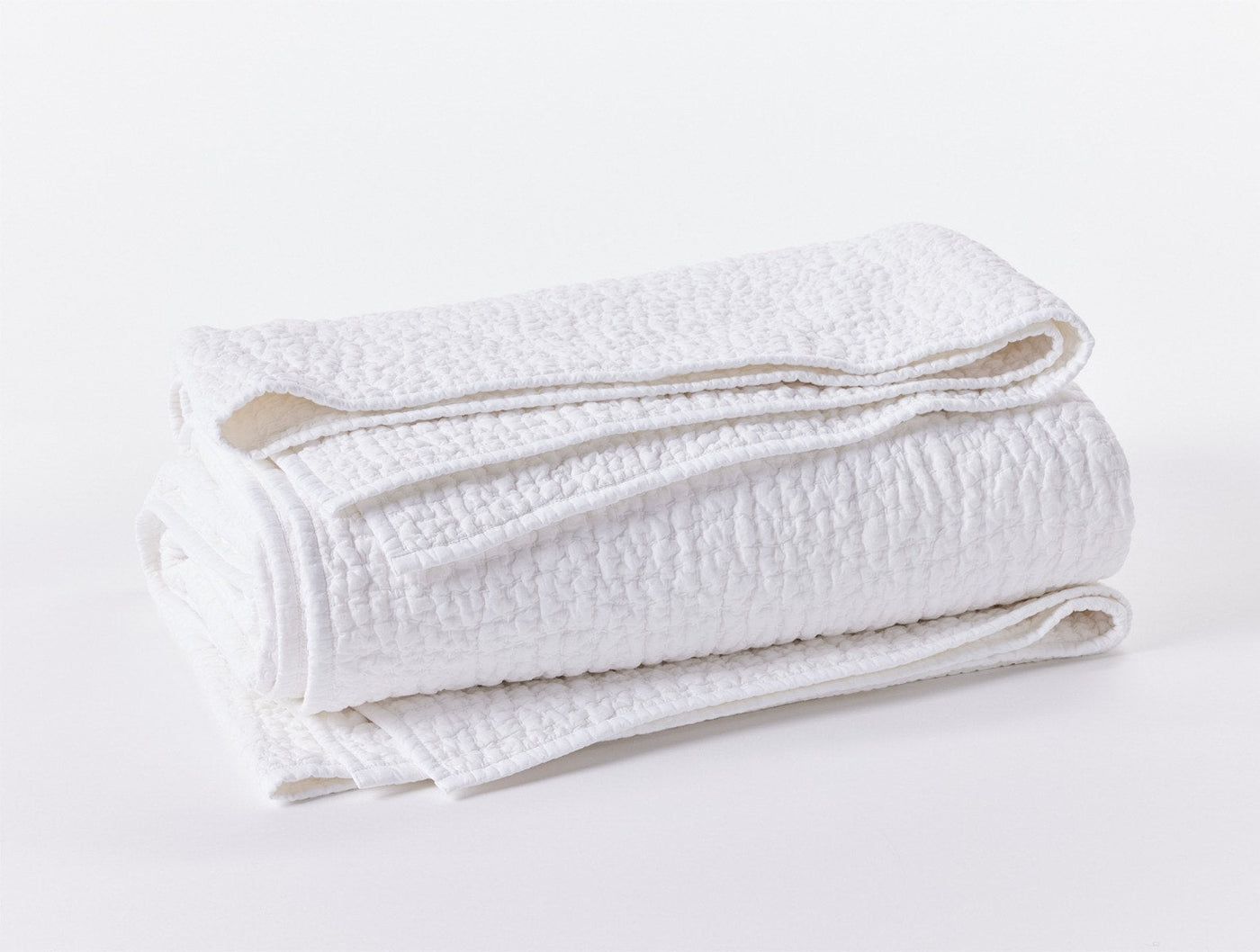 Coyuchi Pebbled Handstitched quilt in white, folded to show textured pebble weave.