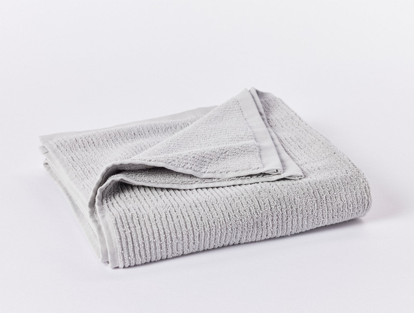 Coyuchi Temescal Ribbed bath towel folded, silver grey ribbed cotton texture visible.