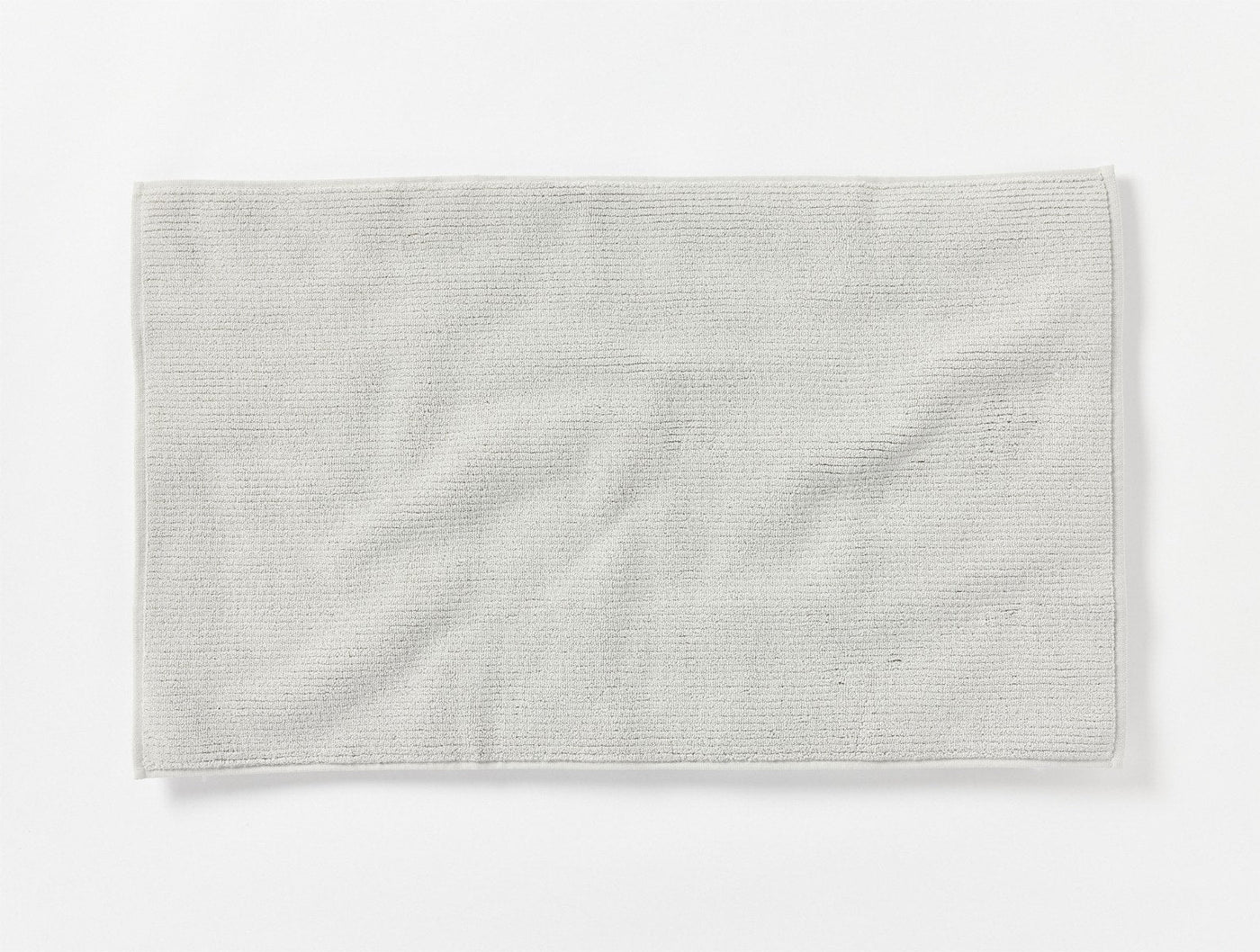 Coyuchi Temescal Ribbed bath rug in ivory, showing subtle rib texture and soft drape.