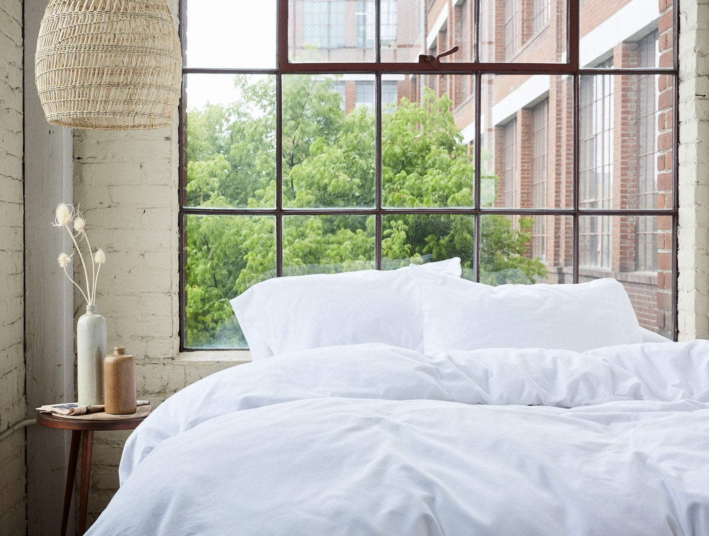 White flannel pillowcases on a made bed, styled near a large industrial window.