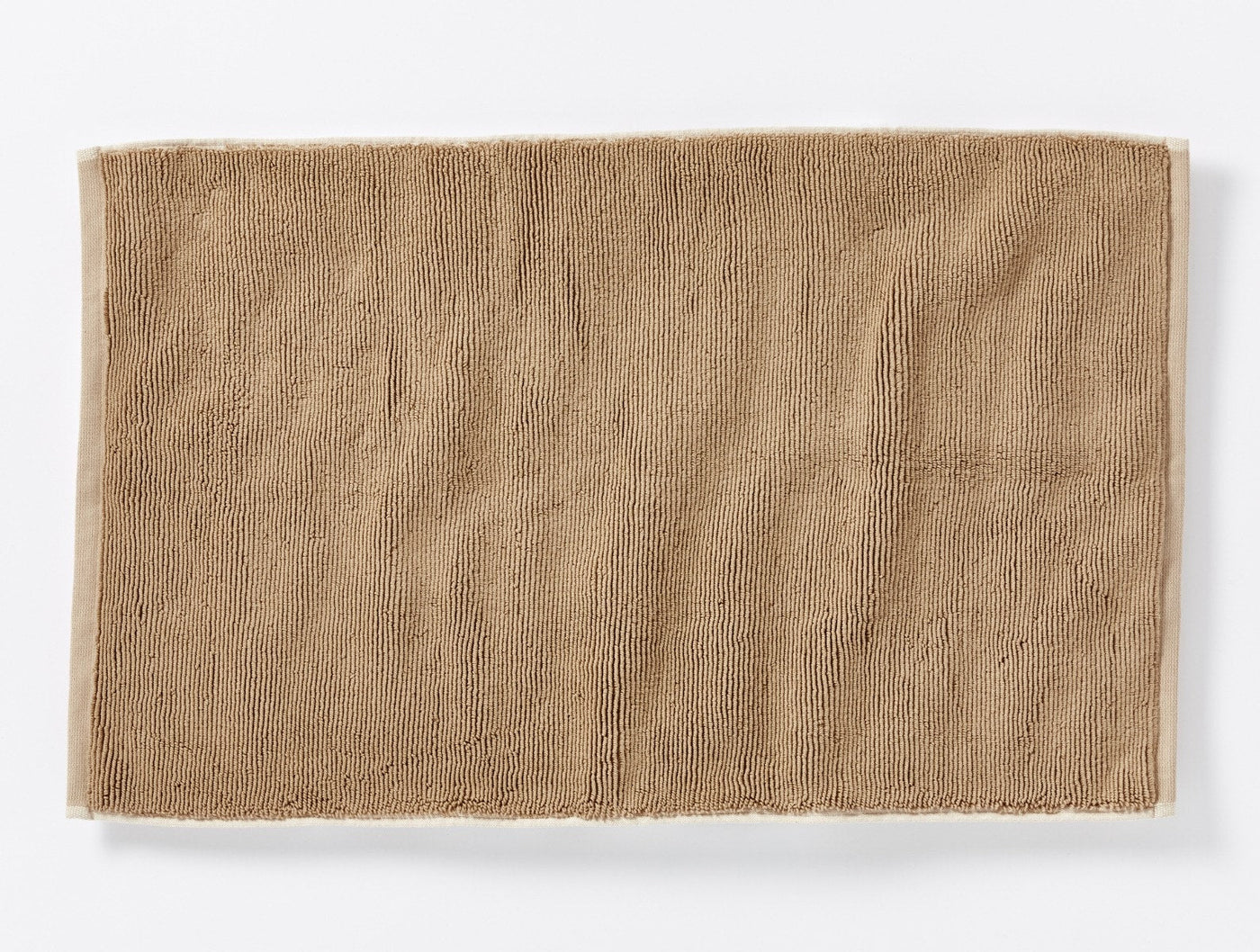 Coyuchi Cloud Loom bath rug in warm tan, flat lay showing textured cotton pile surface.