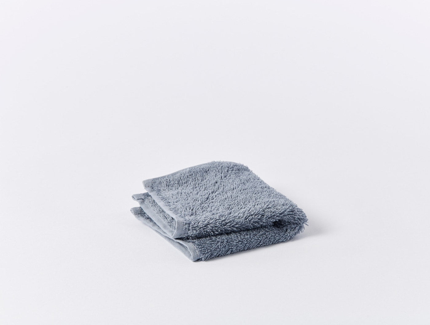 Coyuchi Cloud Loom wash cloth folded flat, slate blue terry loop texture.