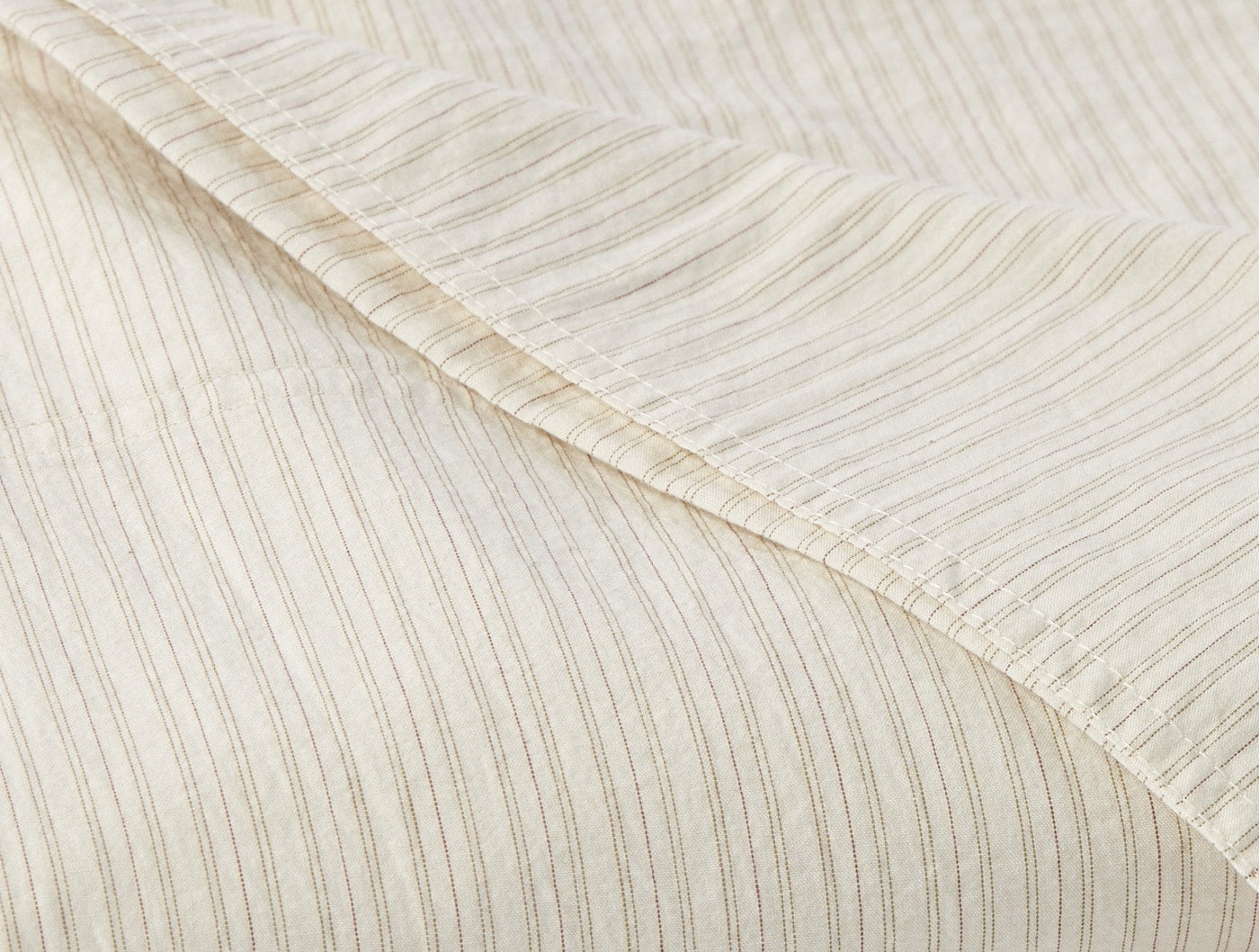 Close-up of Coyuchi Crinkled Percale fitted sheet hem, ivory with subtle stripe texture.