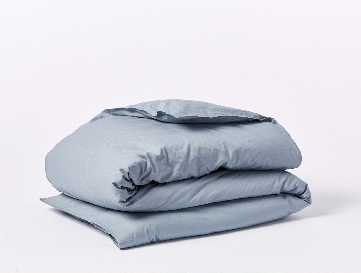 Coyuchi Crinkled Percale duvet cover folded neatly, shown in slate blue.