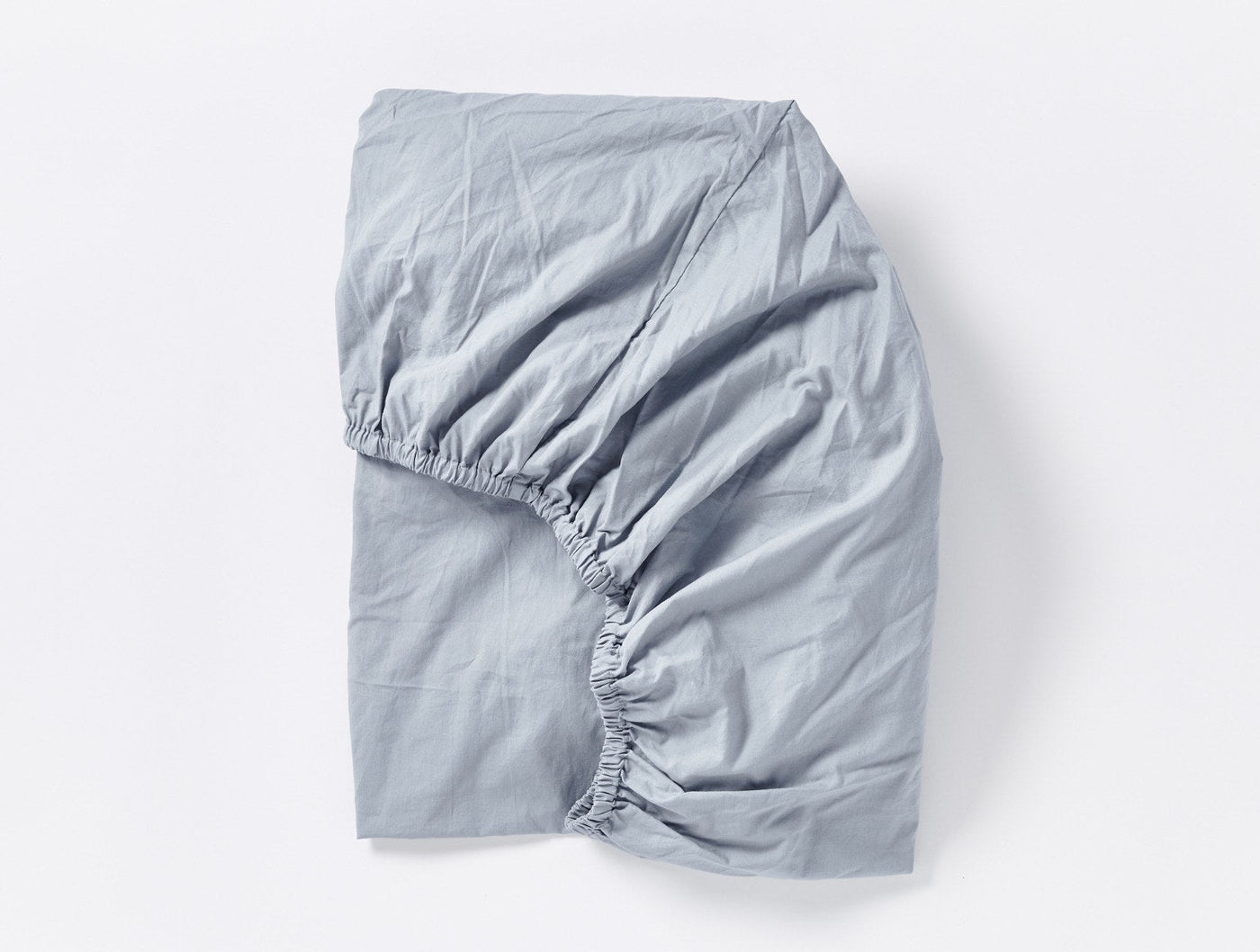 Coyuchi Crinkled Percale fitted sheet in mist blue, folded to show elasticized corners.