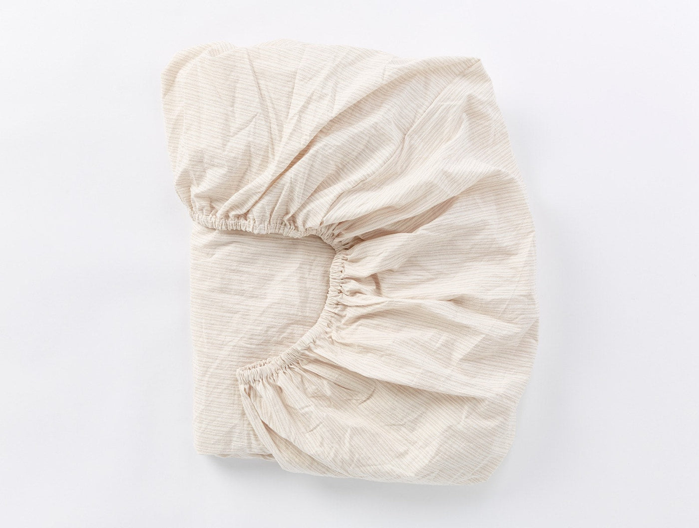 Fitted sheet folded flat, showing elasticated corners and crinkled ivory percale texture.