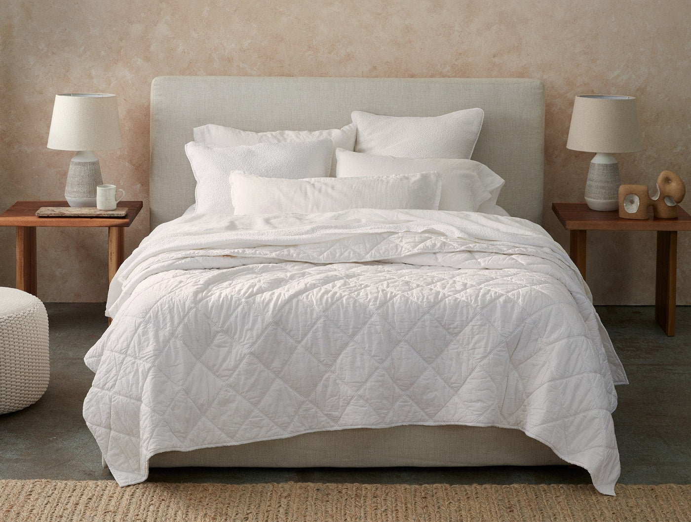 Coyuchi Diamond-Stitched Cotton Comforter in white, styled on a made bed with layered pillows.