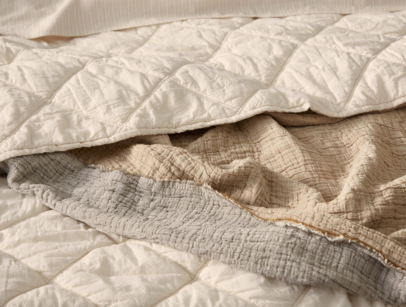 Close-up of Coyuchi Diamond-Stitched Cotton Comforter layers in ivory and natural linen tones.