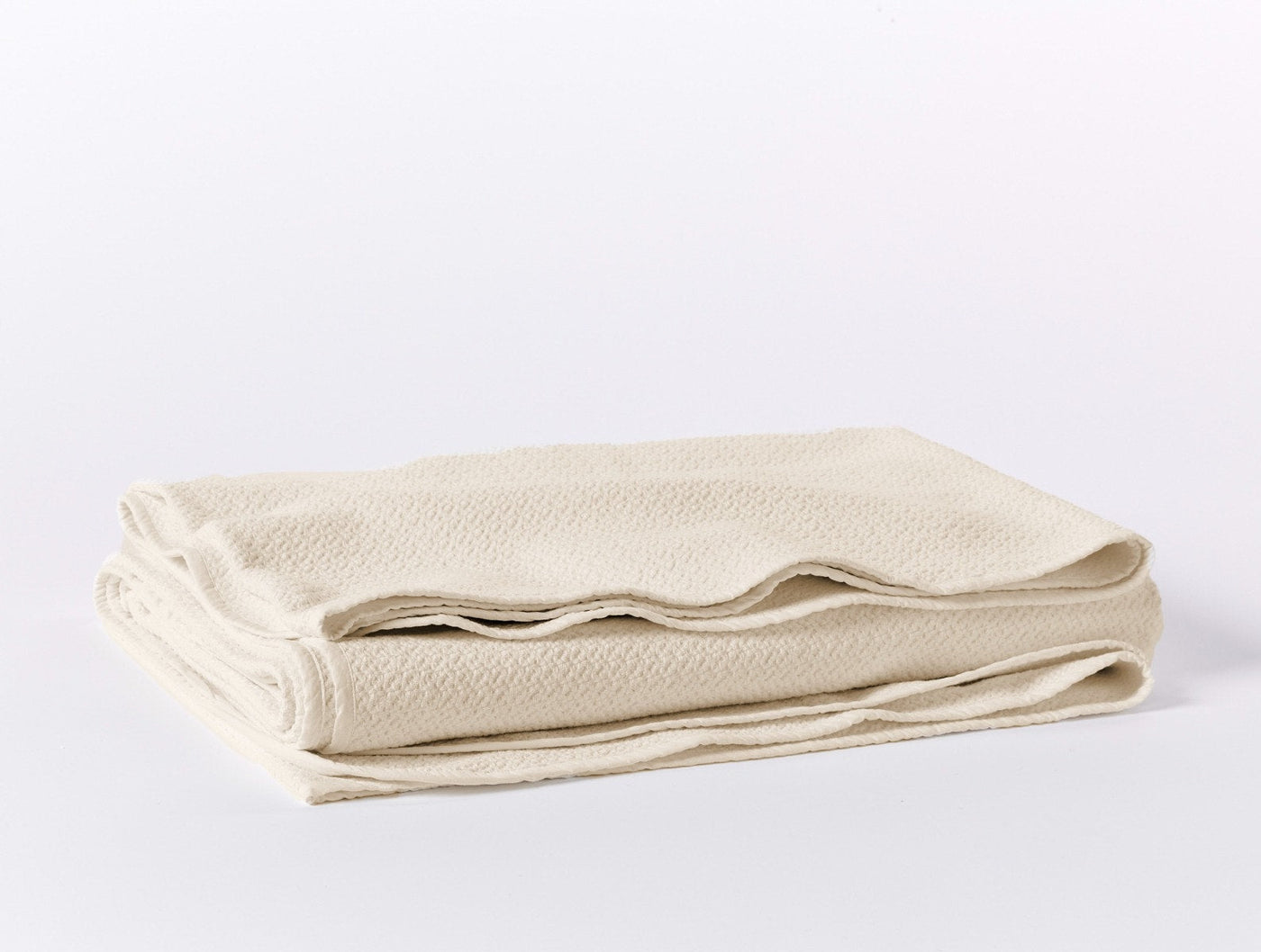 Ivory honeycomb-weave blanket neatly folded, showing textured surface detail.
