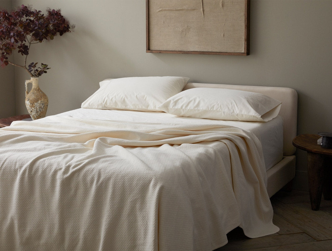 Ivory honeycomb-weave blanket draped over a made bed in a soft neutral bedroom.