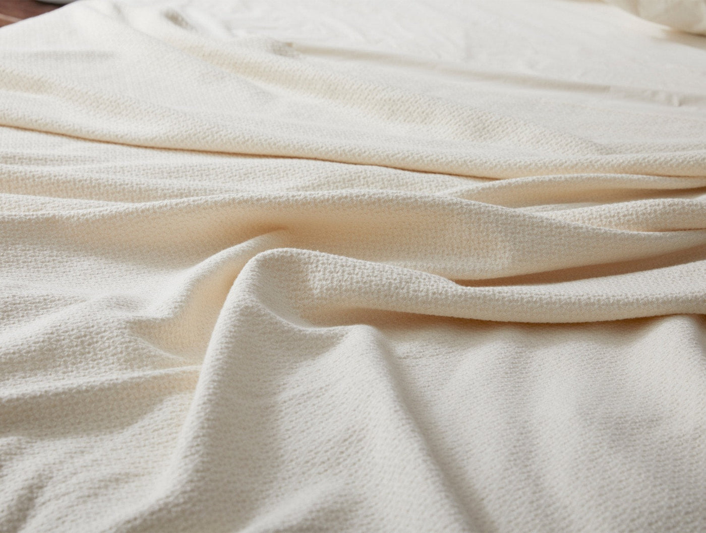 Close-up of ivory Coyuchi Honeycomb blanket showing textured weave and soft draping.