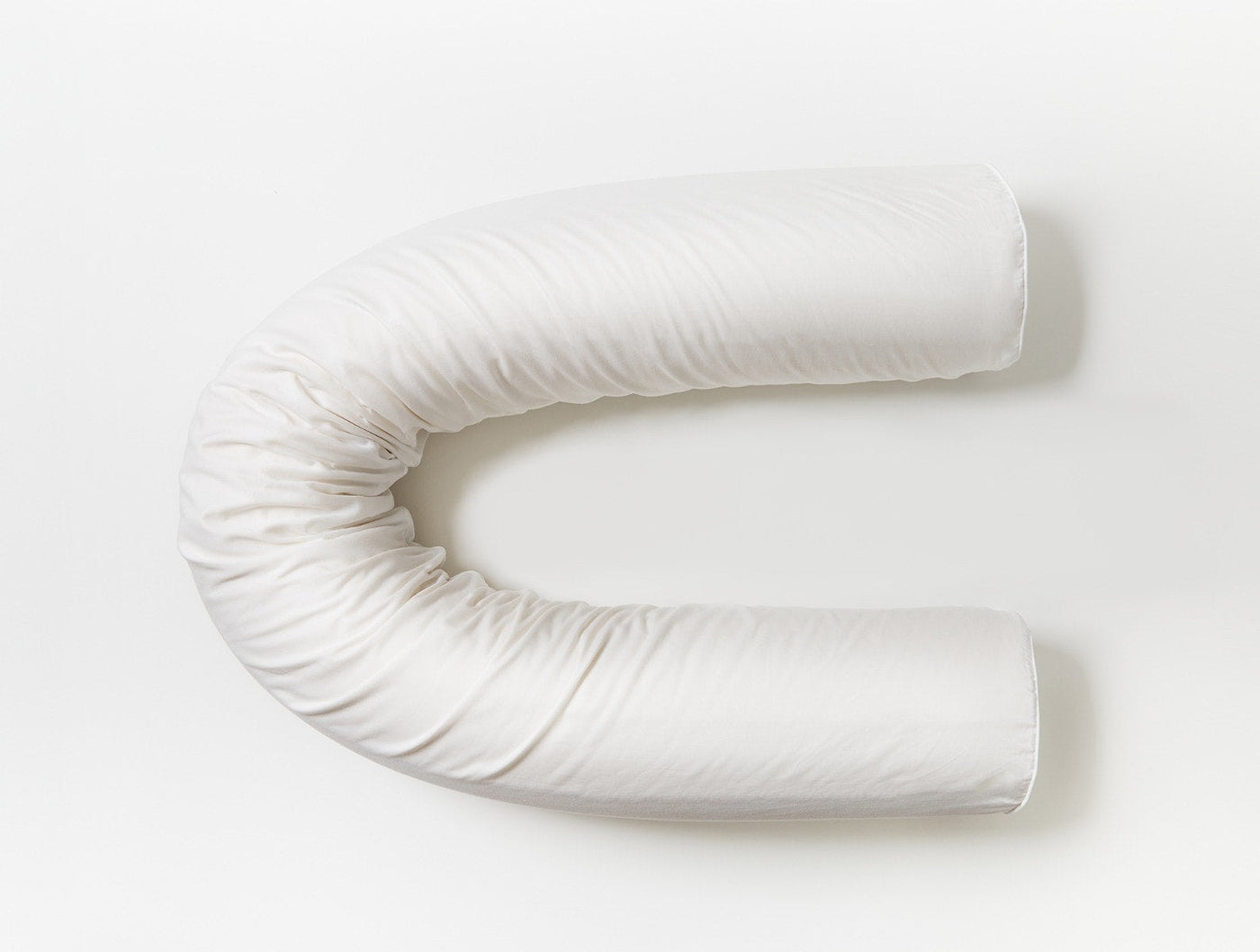 U-shaped white latex body pillow curved into horseshoe form on white background.