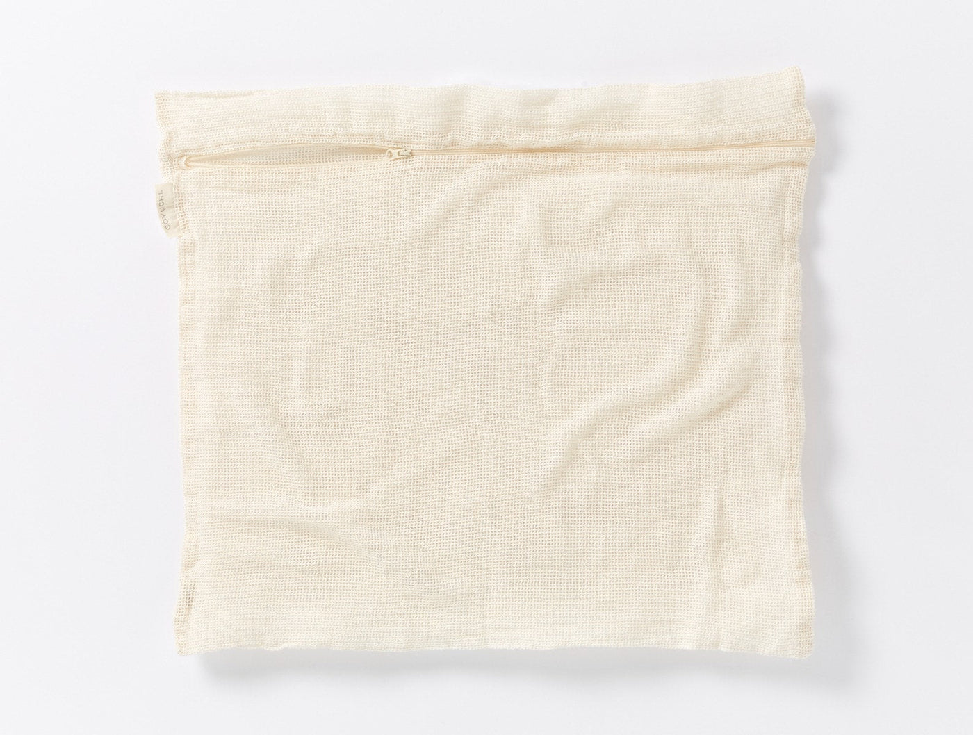 Coyuchi Conserve laundry bag, ivory mesh fabric with zipper closure, flat lay view.