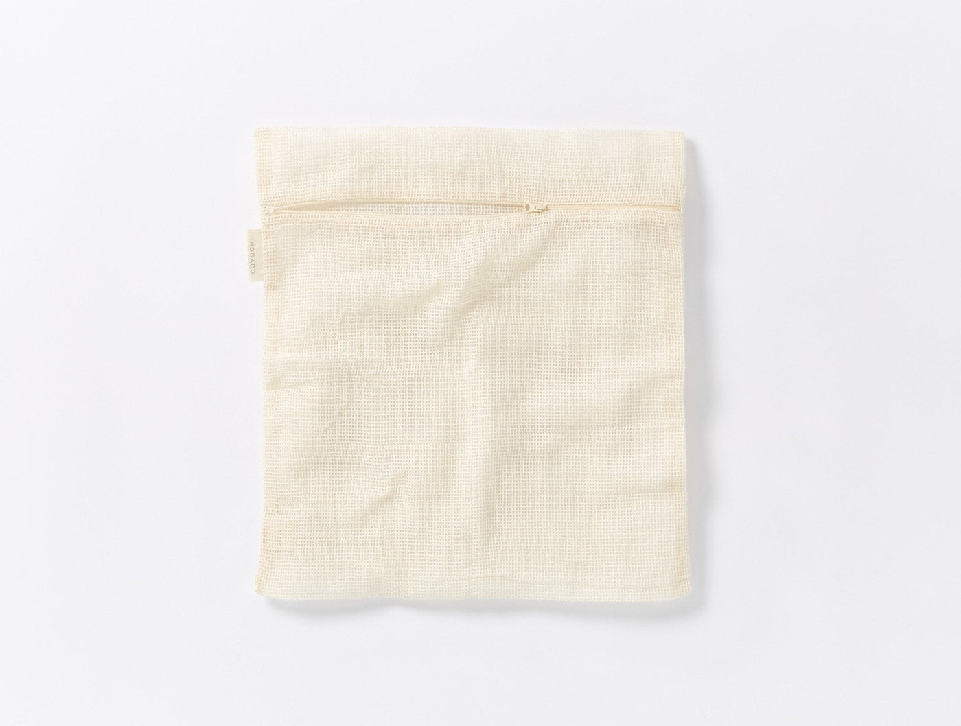 Coyuchi Conserve laundry bag in ivory, flat lay showing mesh weave texture and zipper closure.