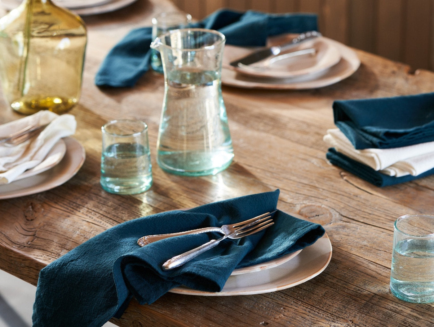 Coyuchi Sonoma Textured napkins in teal styled on rustic wood table with place settings.