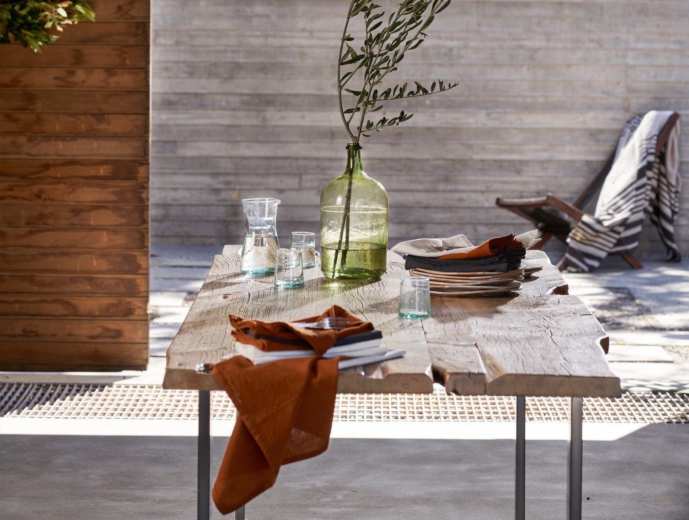 Rust linen napkins styled on an outdoor table with plates and glassware in natural light.