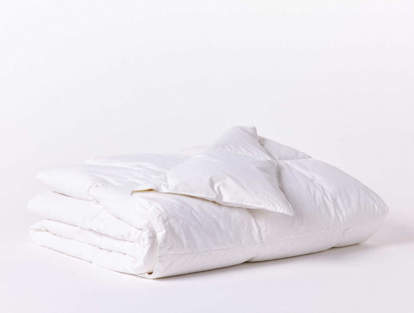 Coyuchi Lightweight Down duvet insert in white, neatly folded showing lofty fill.