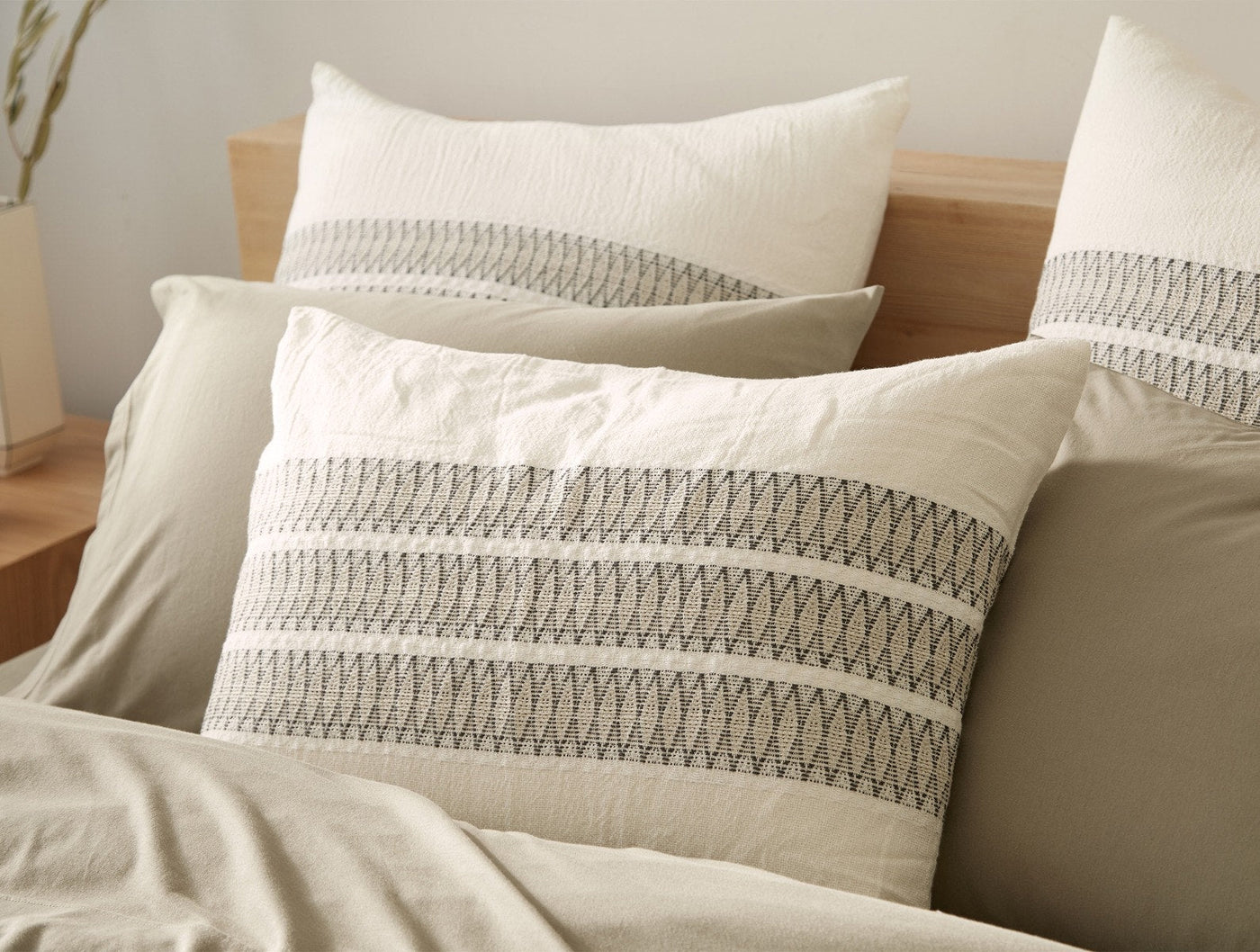 Close-up of Coyuchi Lost Coast sham showing textured zigzag embroidery stripes in grey on ivory organic cotton.
