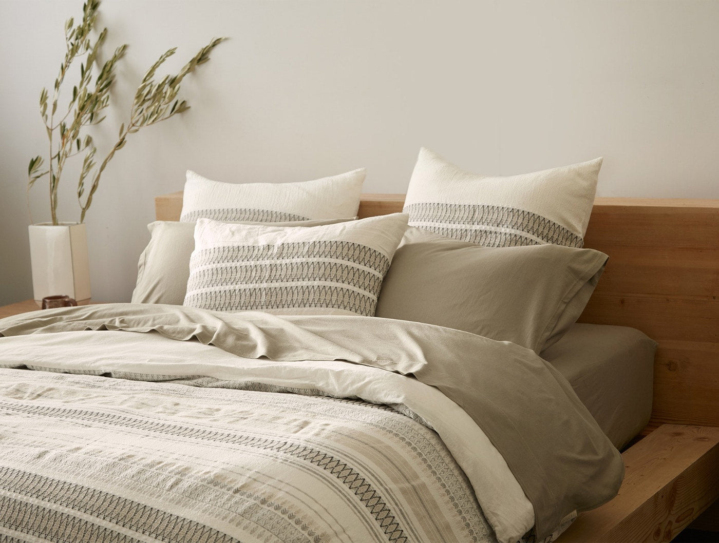 Coyuchi Lost Coast duvet cover styled on bed with matching shams, ivory and sage striped texture.