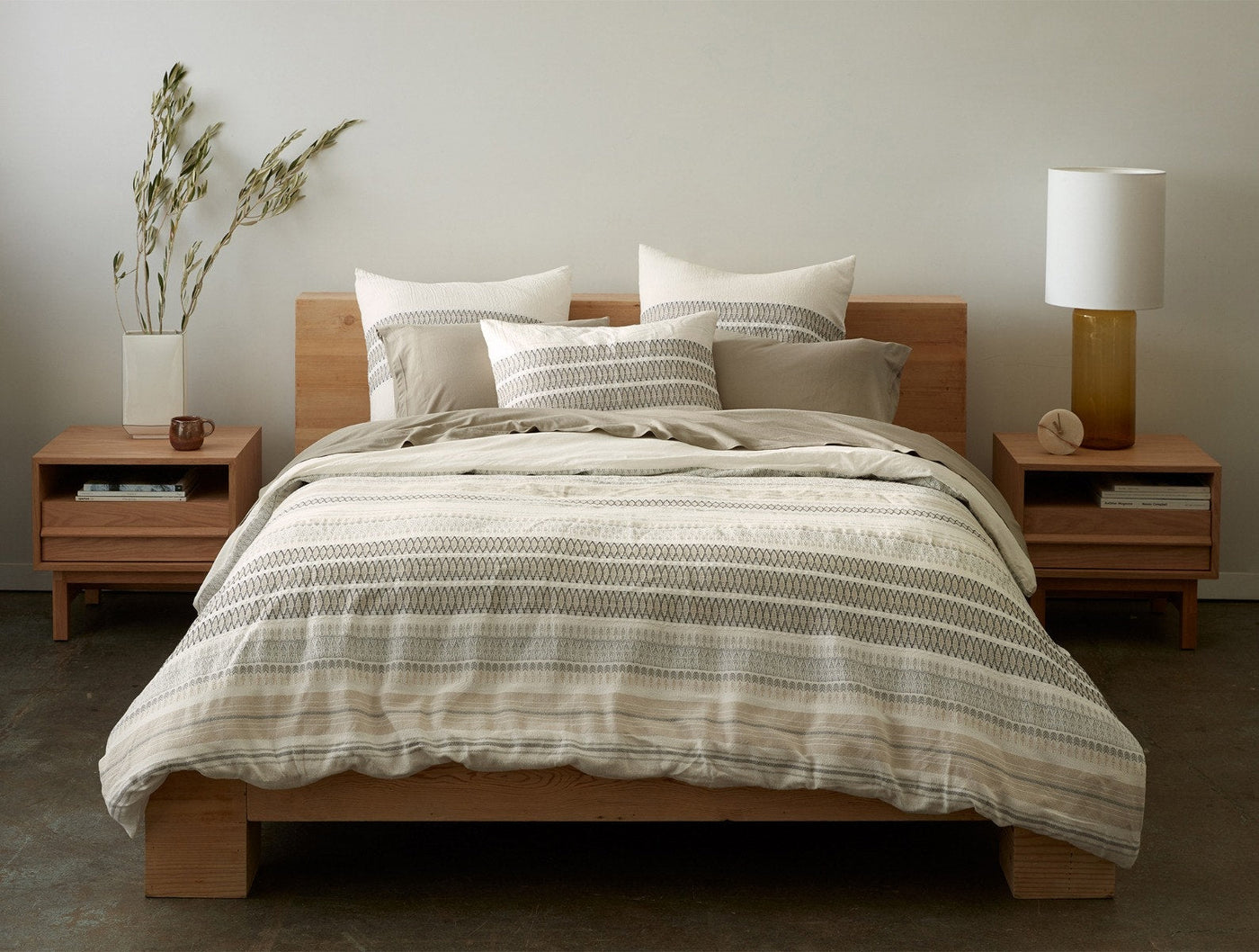 Coyuchi Lost Coast sham styled on a made bed with striped linen duvet in a warm neutral bedroom.