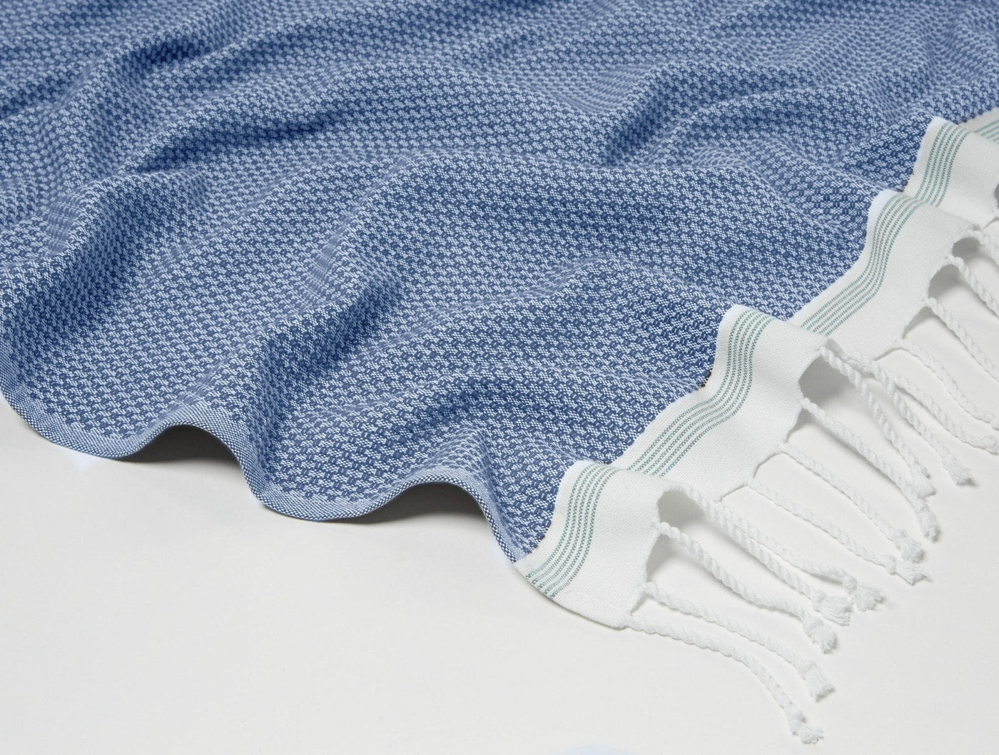 Close-up of Coyuchi Mediterranean throw corner with blue honeycomb weave and striped fringe.