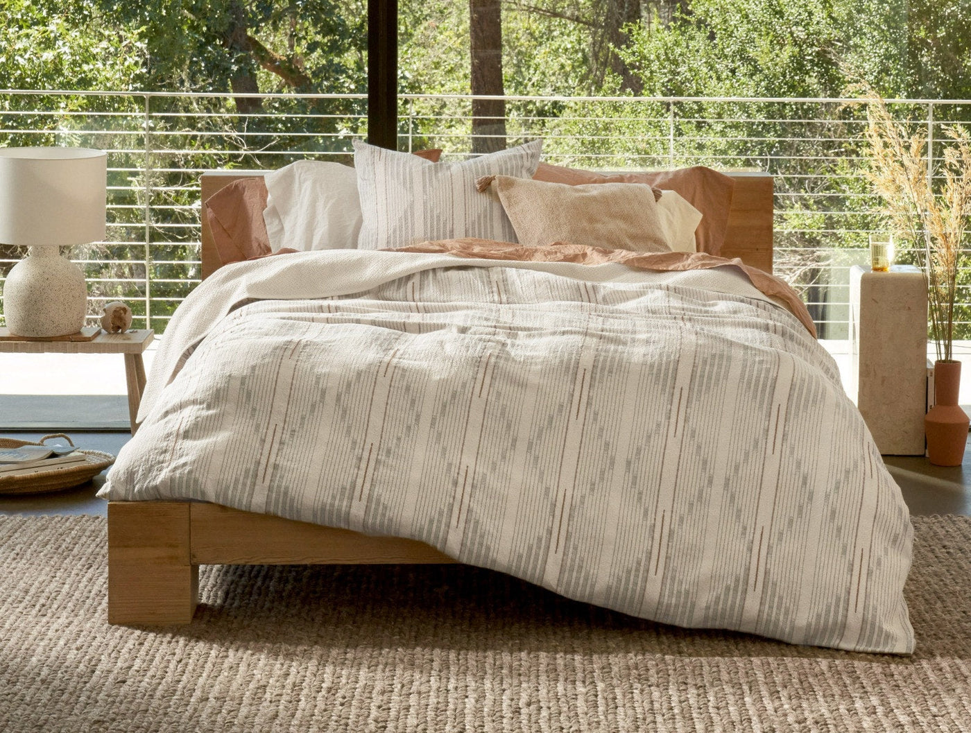 Ivory duvet with woven grey ikat stripe pattern on bed, styled with blush and neutral pillows.