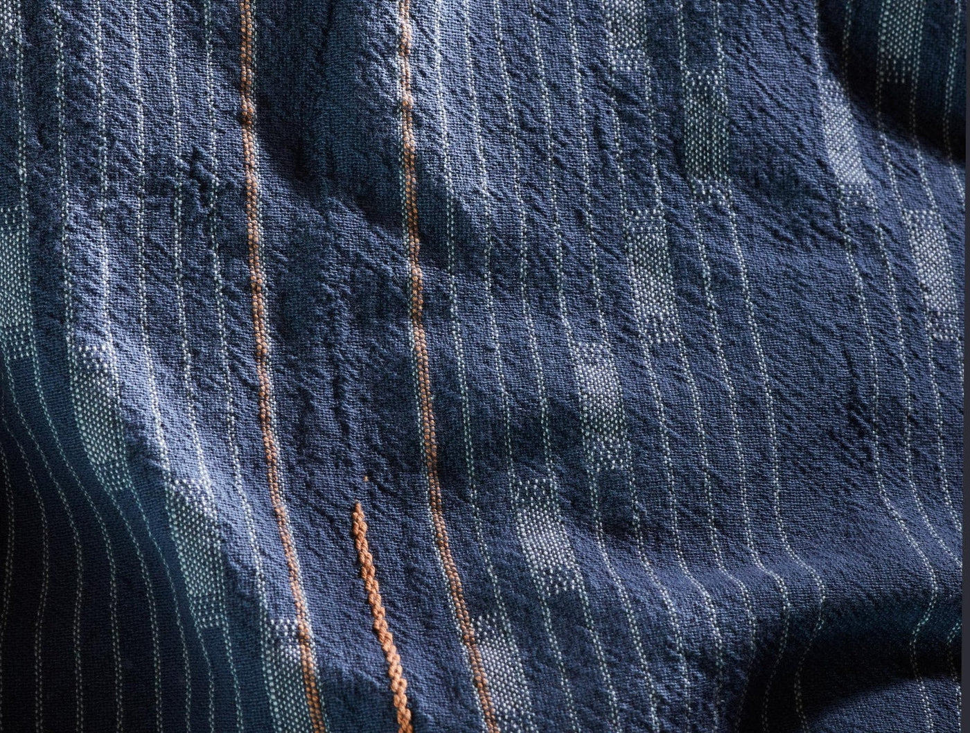 Close-up of Coyuchi Morelia duvet cover weave with navy, teal, and amber stripe detail.