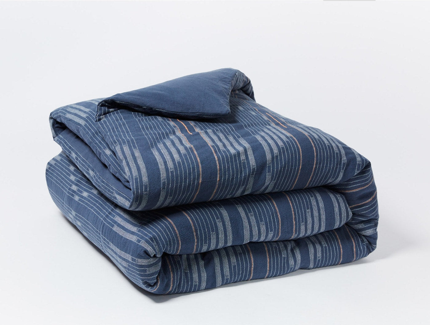 Close-up of folded Morelia duvet cover in navy with brushstroke stripe pattern.