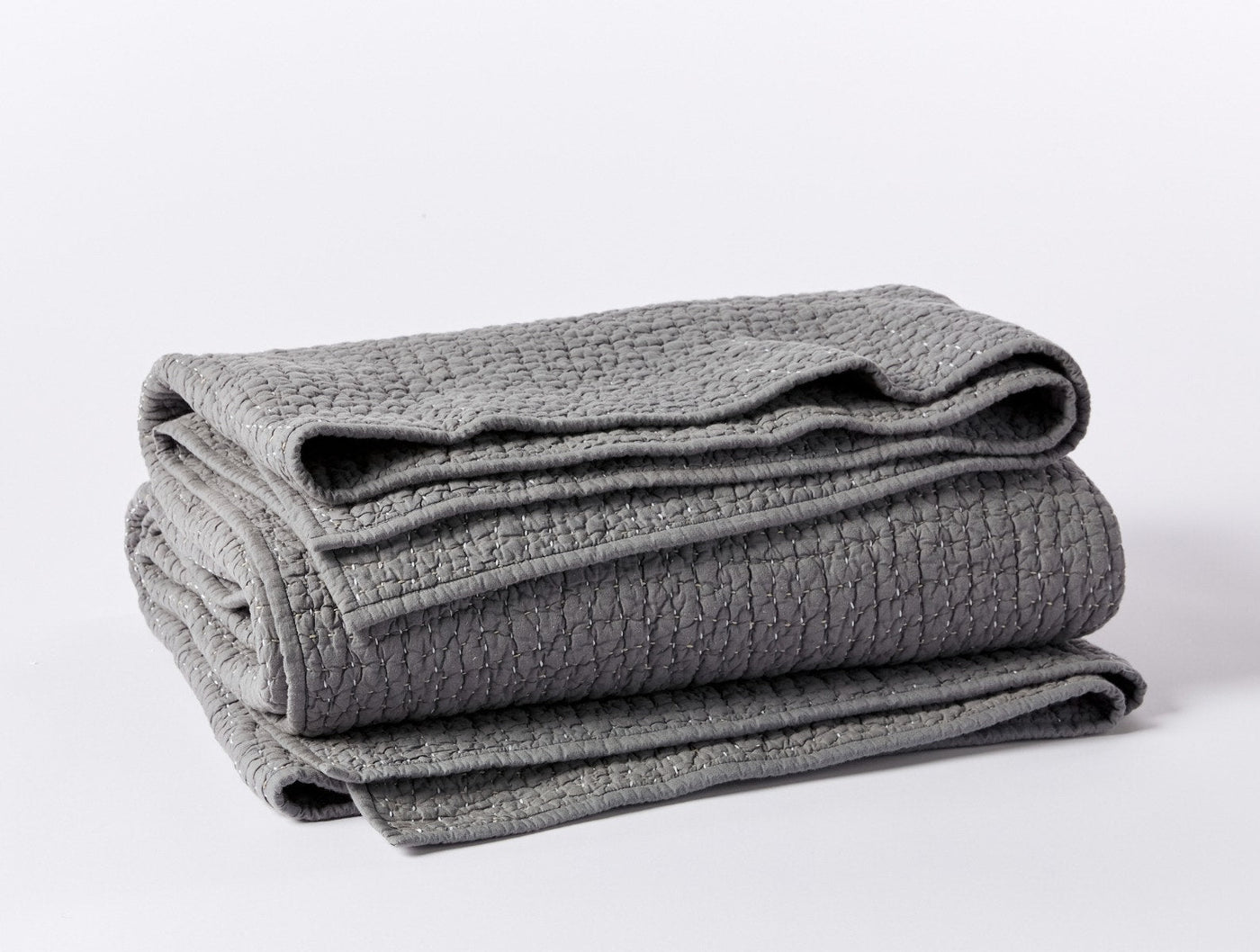 Folded slate grey Coyuchi quilt showing pebbled texture and handstitched detail.