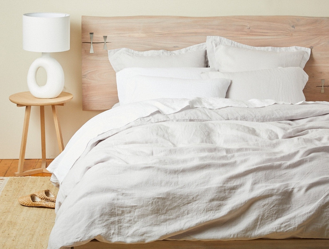 Coyuchi Relaxed Linen duvet cover in white, casually draped on a styled bed with layered pillows.