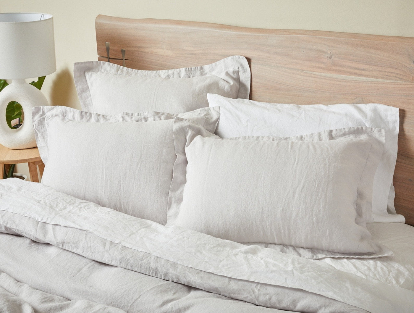 Coyuchi Relaxed Linen duvet and pillows styled on a natural wood bed in white.