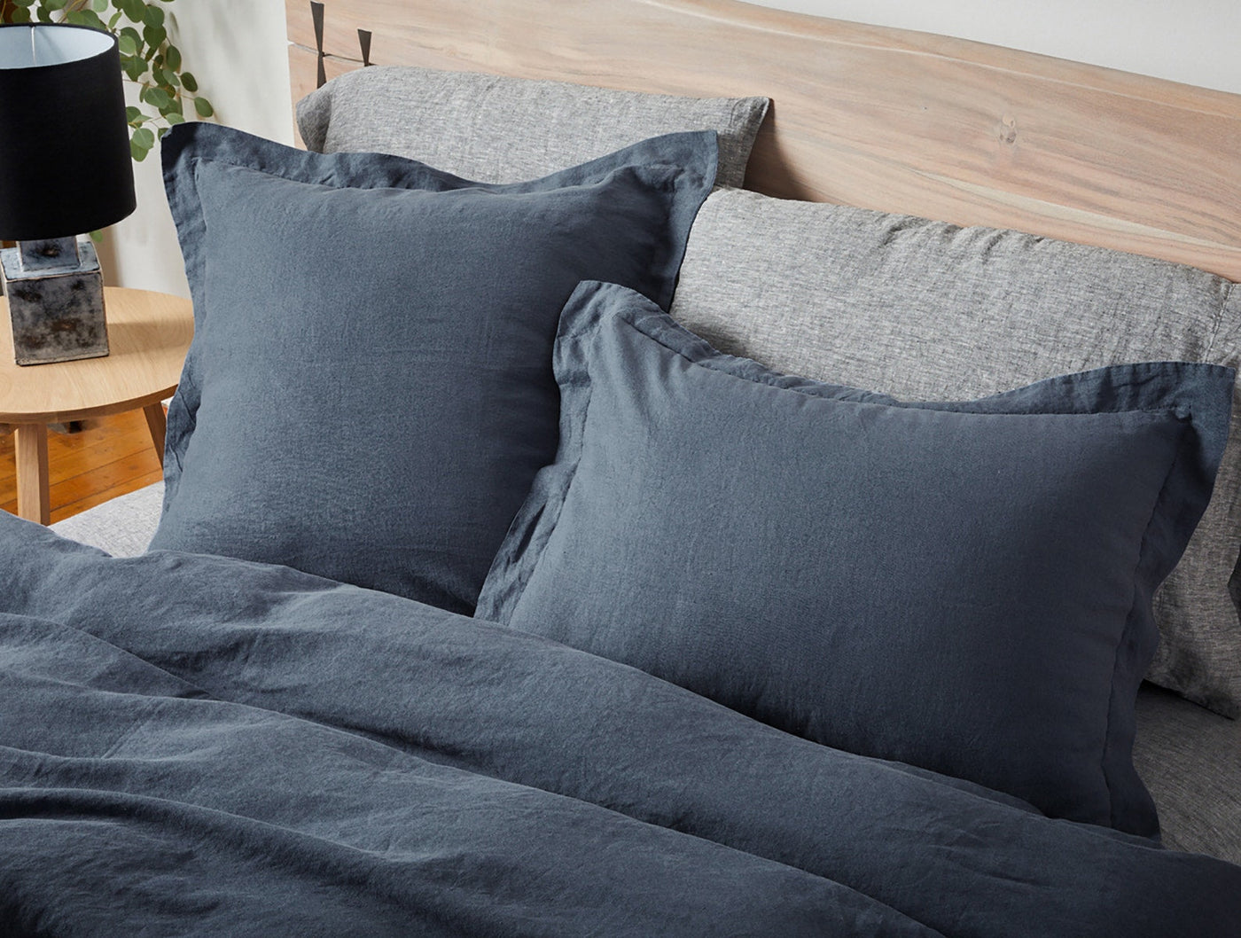 Coyuchi Relaxed Linen shams in slate blue, shown styled on a made bed with natural linen bedding.