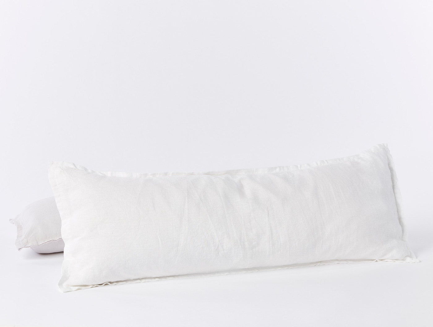 Coyuchi Relaxed Linen long bolster pillow in white with frayed edges, side view.