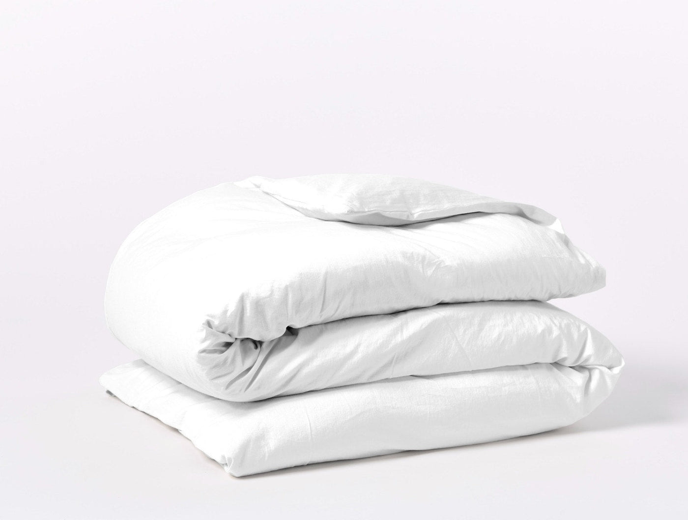 Coyuchi Cloud Soft Sateen duvet cover in white, neatly folded stack on light background.
