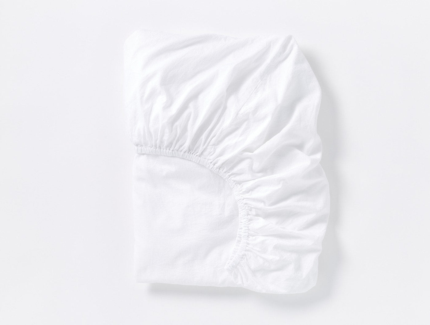 Coyuchi Cloud Soft Sateen fitted sheet in white, folded flat showing elasticized corners.