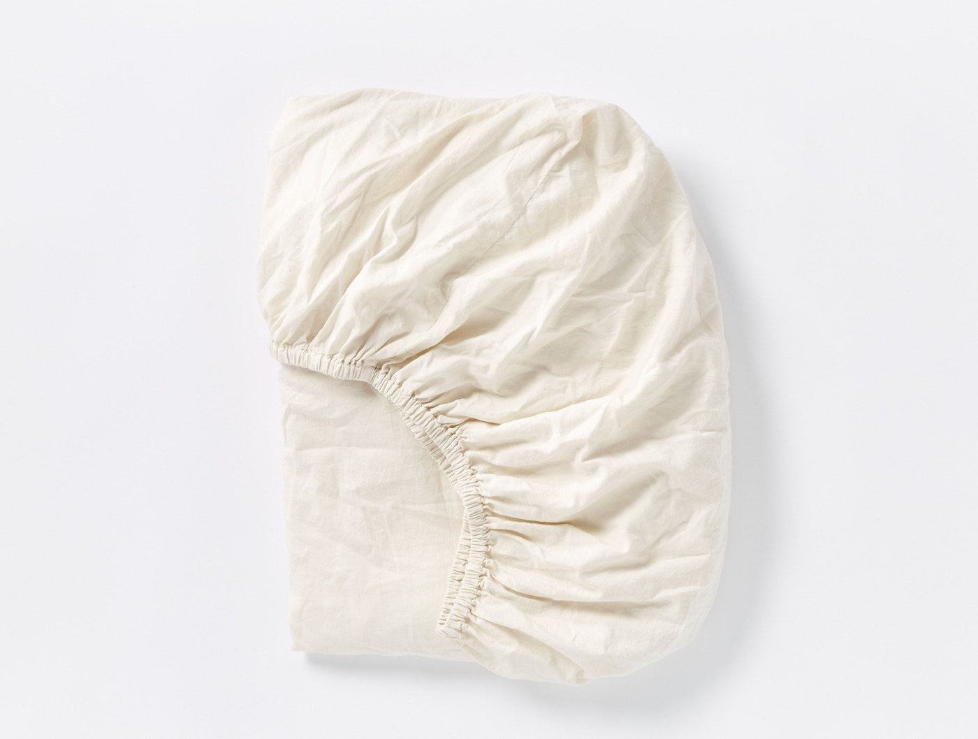 Ivory fitted sheet gathered at corners, showing elastic hem detail and soft sateen fabric texture.