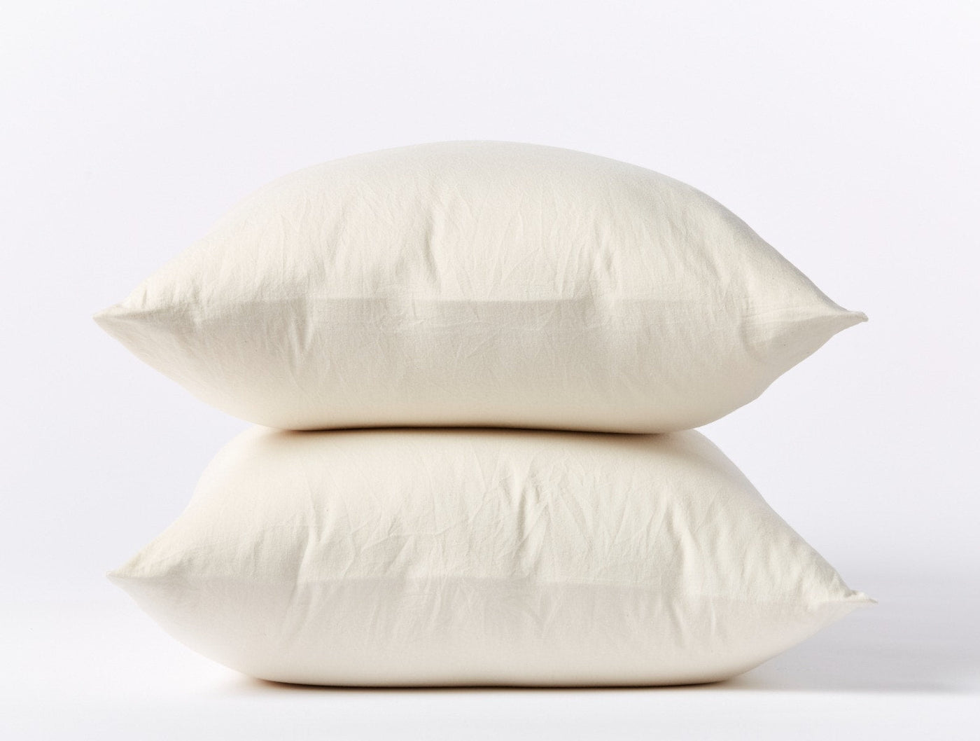 Two ivory Coyuchi Cloud Soft Sateen pillowcases stacked, showing smooth finish and plump fill.
