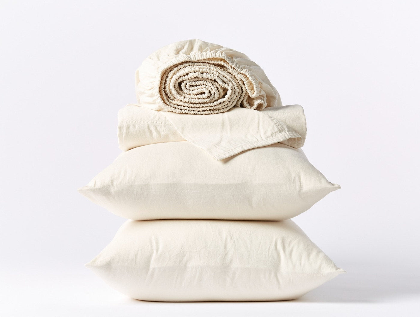 Ivory sateen sheet set stacked with two pillowcases and a rolled fitted sheet.