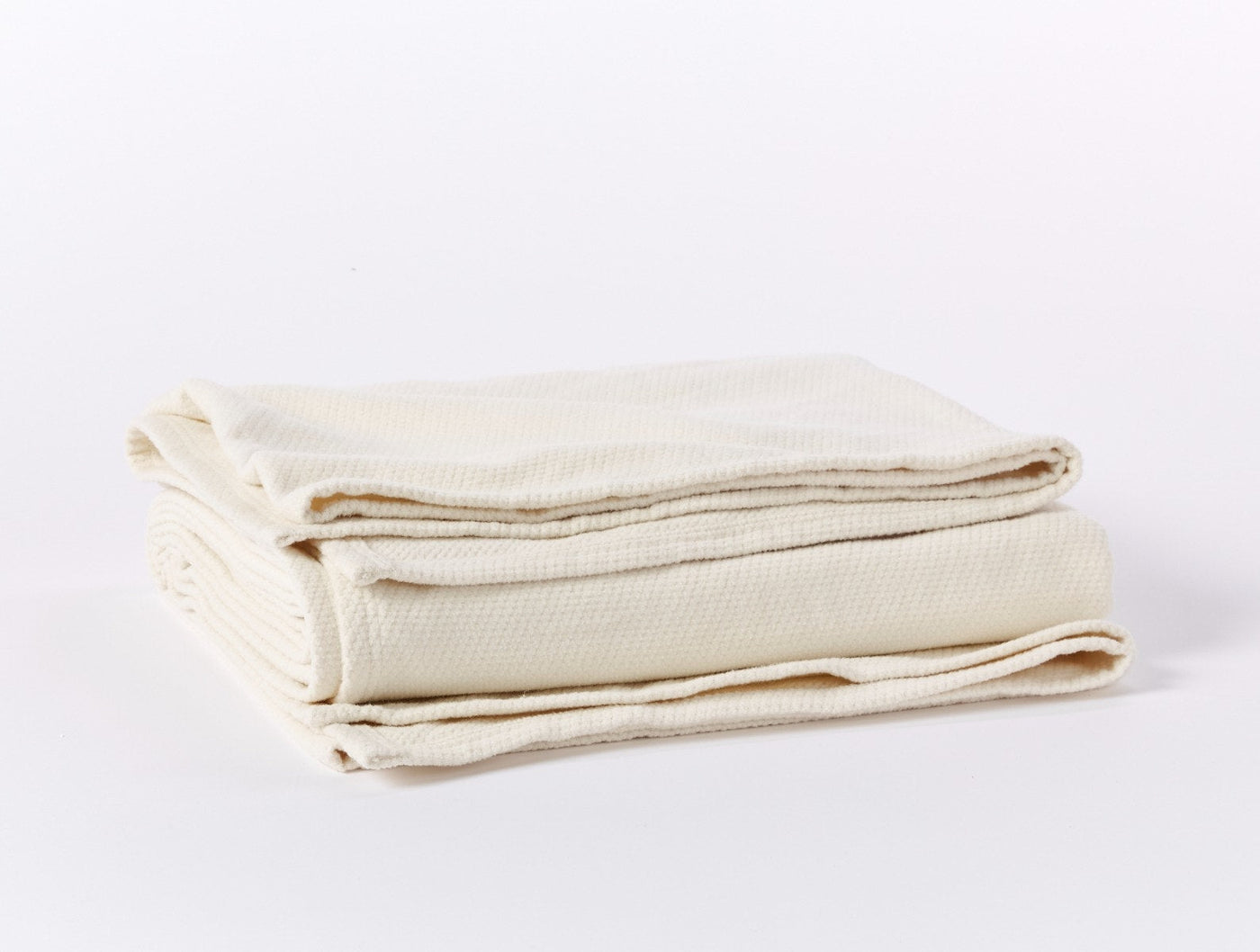 Ivory woven blanket folded to show textured weave and finished edges.