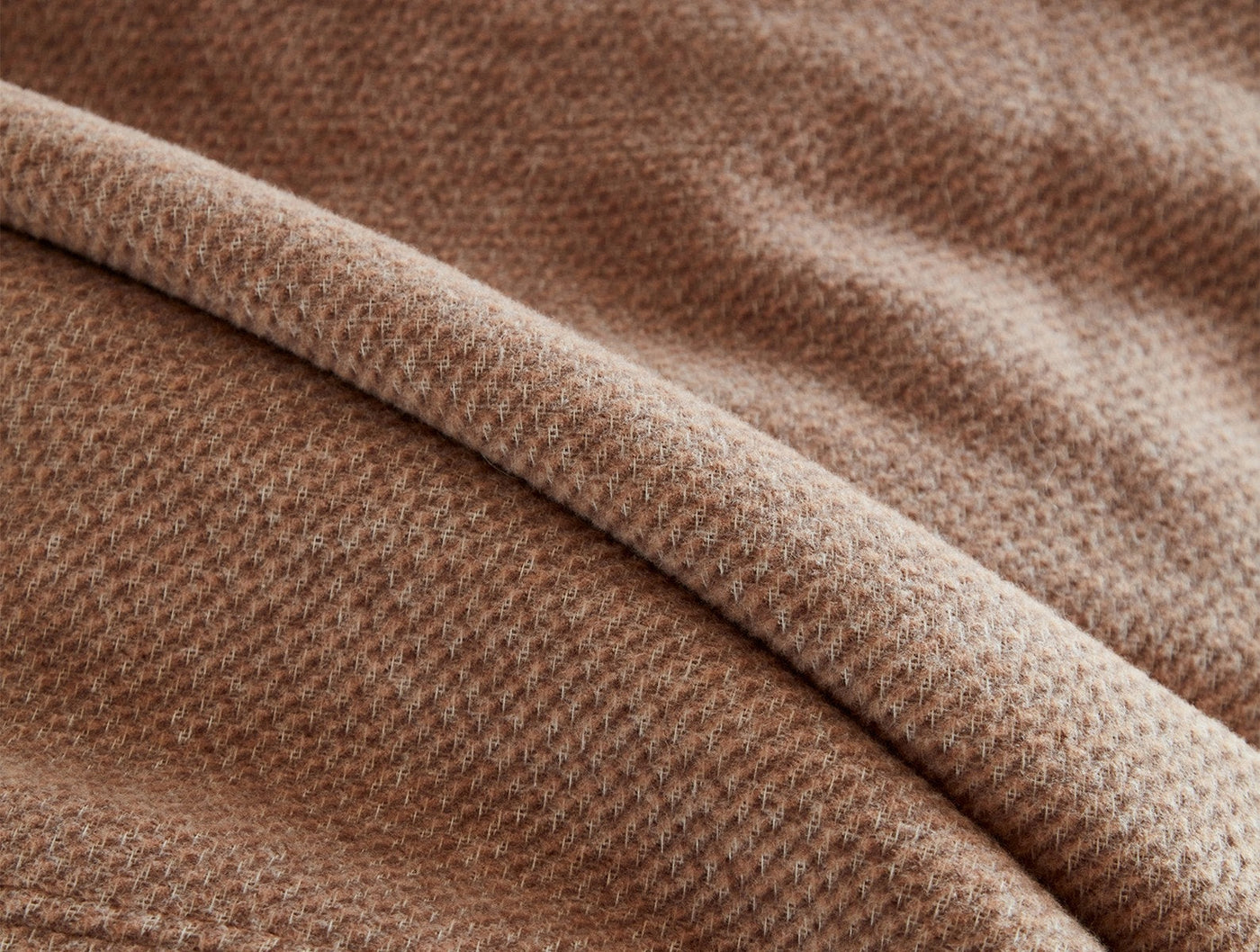 Close-up of Coyuchi Sequoia blanket's toffee waffle-knit texture with soft folded drape.