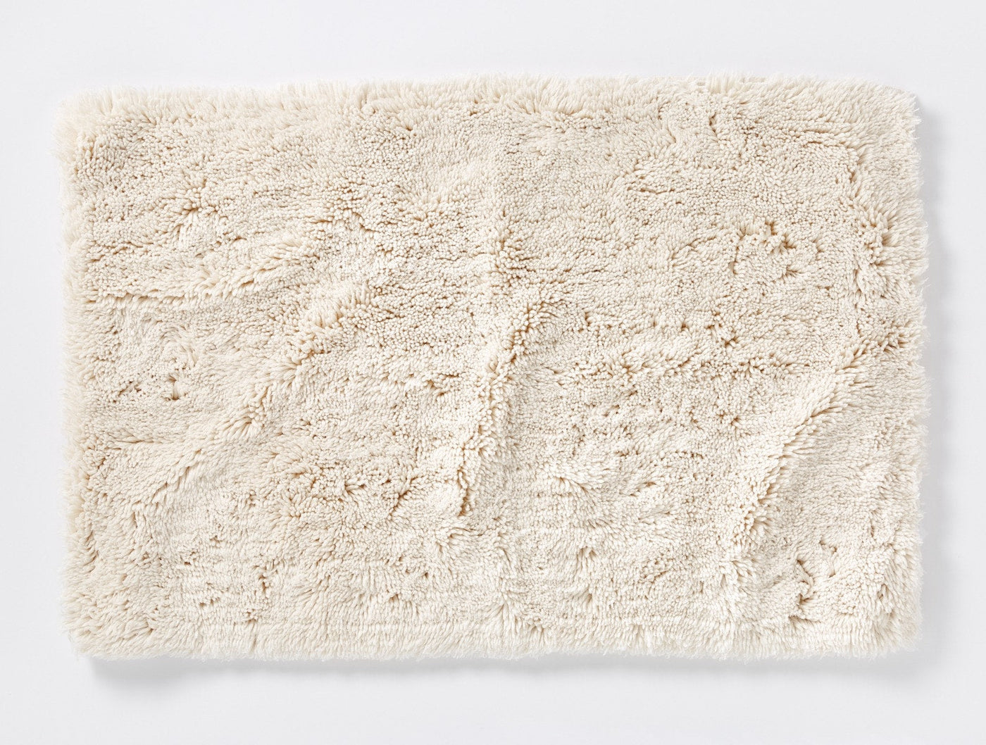 Overhead view of ivory Coyuchi shag bath rug showing plush texture and tonal pattern.