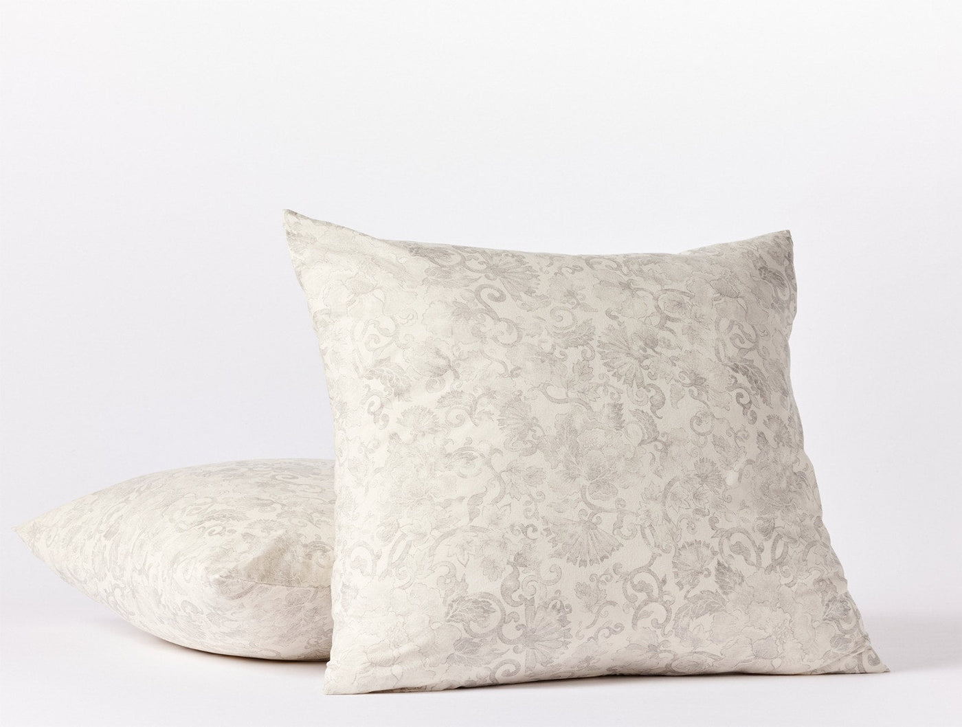 Close-up of two stacked ivory Coyuchi Solana Print shams with tone-on-tone floral damask.