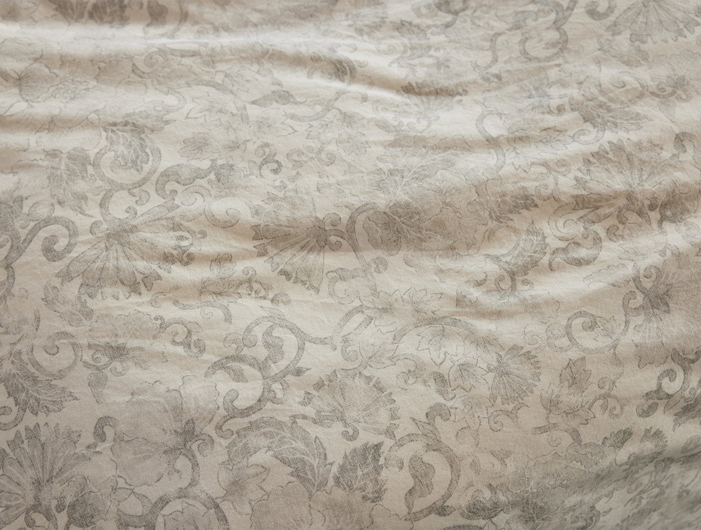 Close-up of Coyuchi Solana Print duvet cover showing tonal damask floral pattern in warm linen.