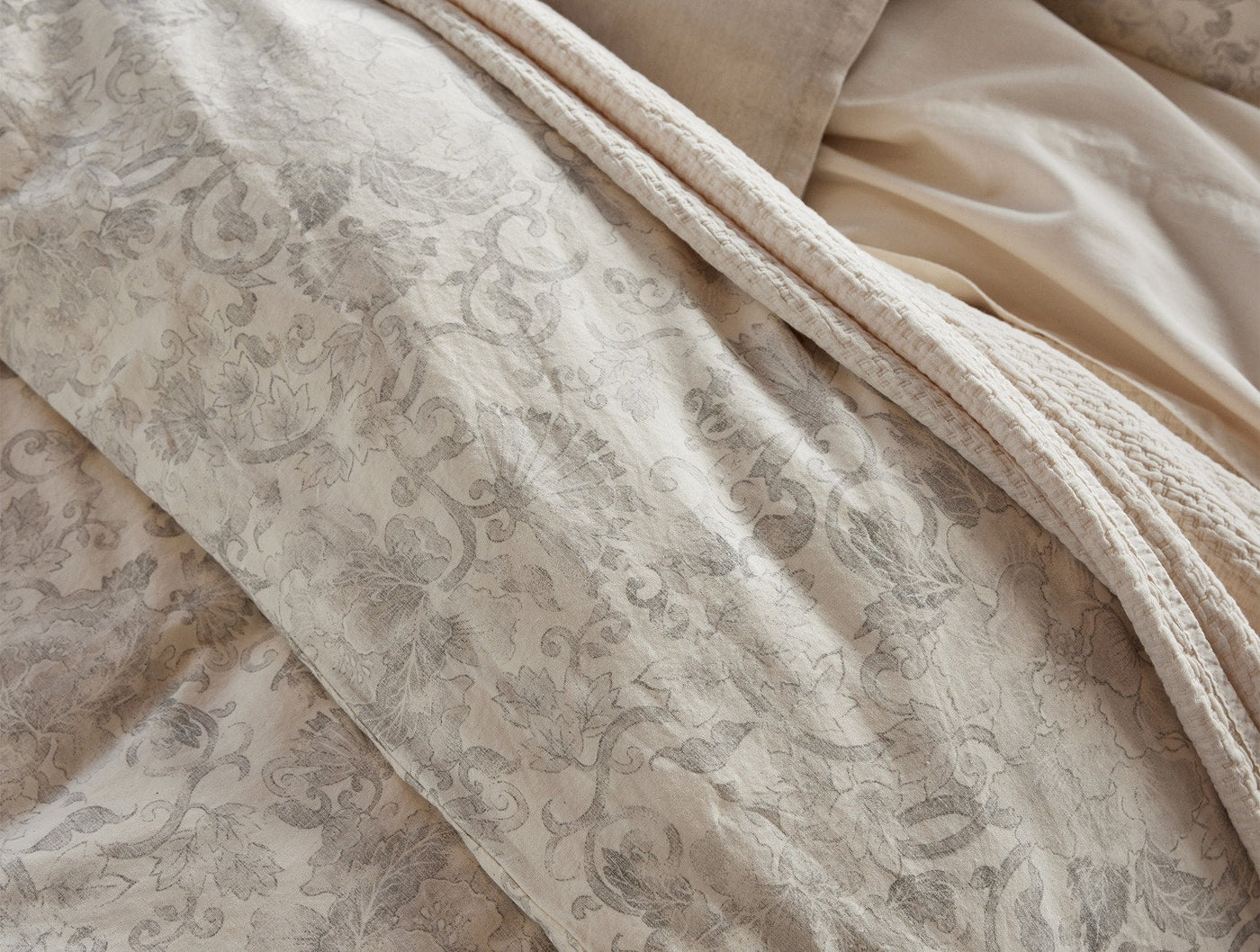 Close-up of Coyuchi Solana Print sham in ivory, showing intricate floral damask weave detail.